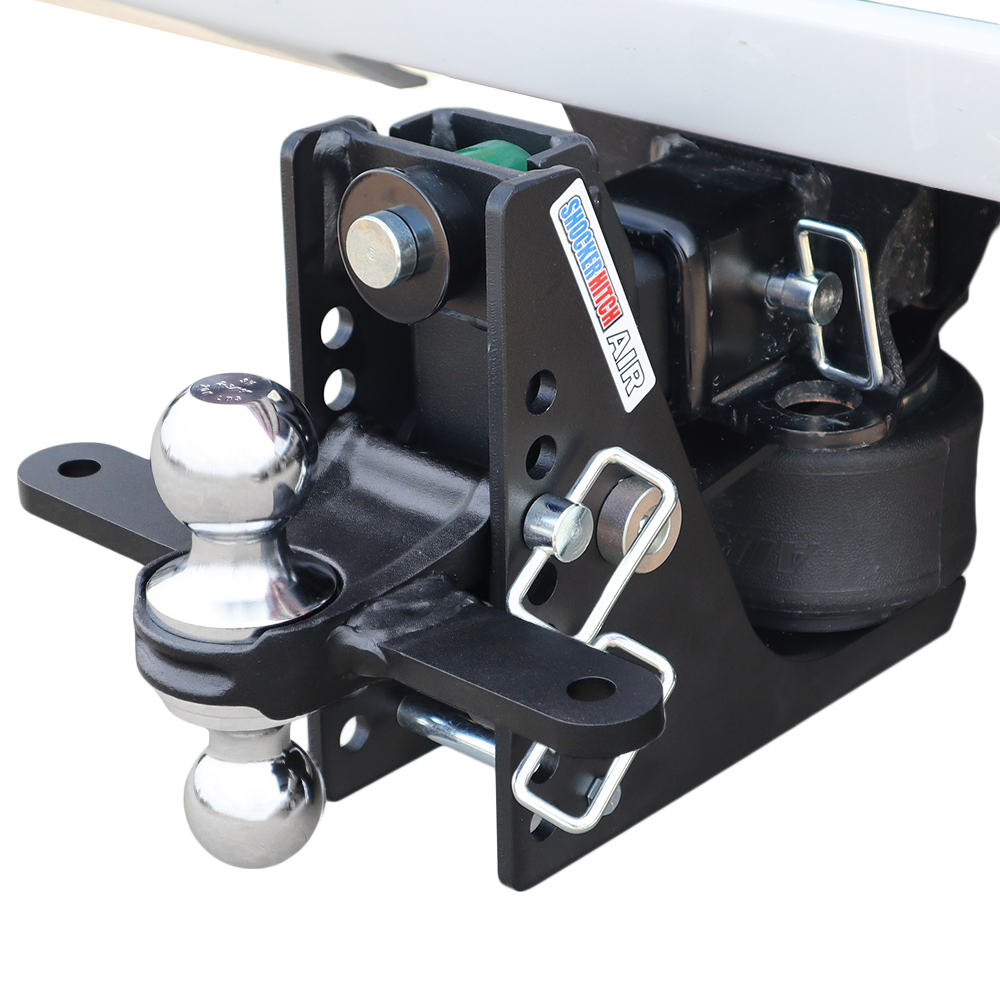 Close-up of a trailer hitch assembly with a shiny ball hitch, black mounting plate, and securing pin ready to connect a trailer